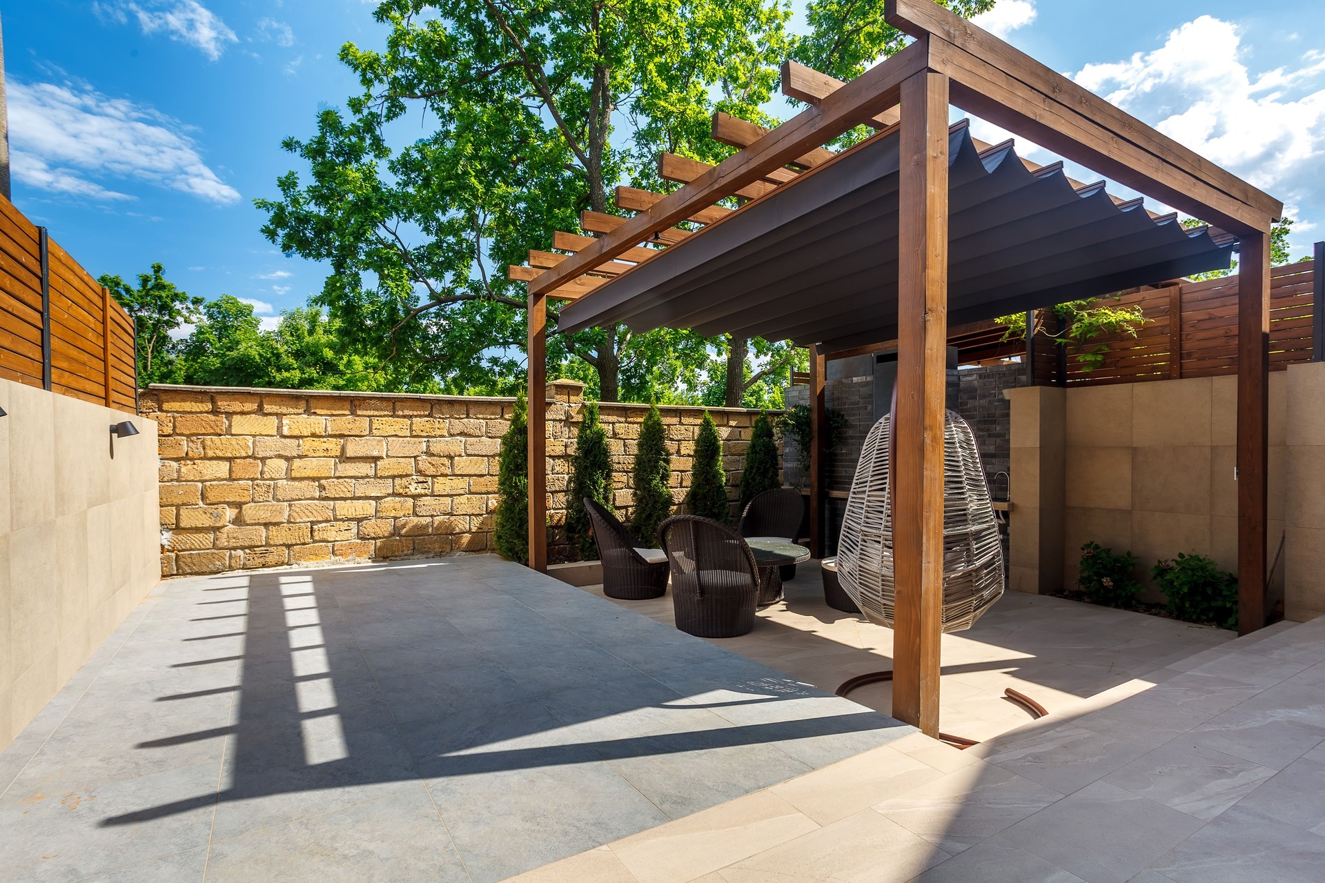 Backyard outdoor bbq zone with pergola, fireplace and hanging chair. Summer party place