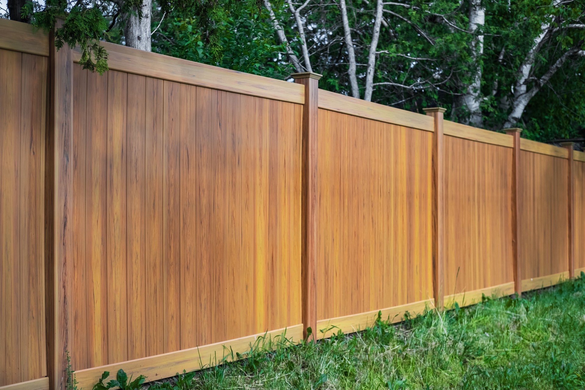 Nice new wooden fence around house. Wooden fence with green lawn. Street photo